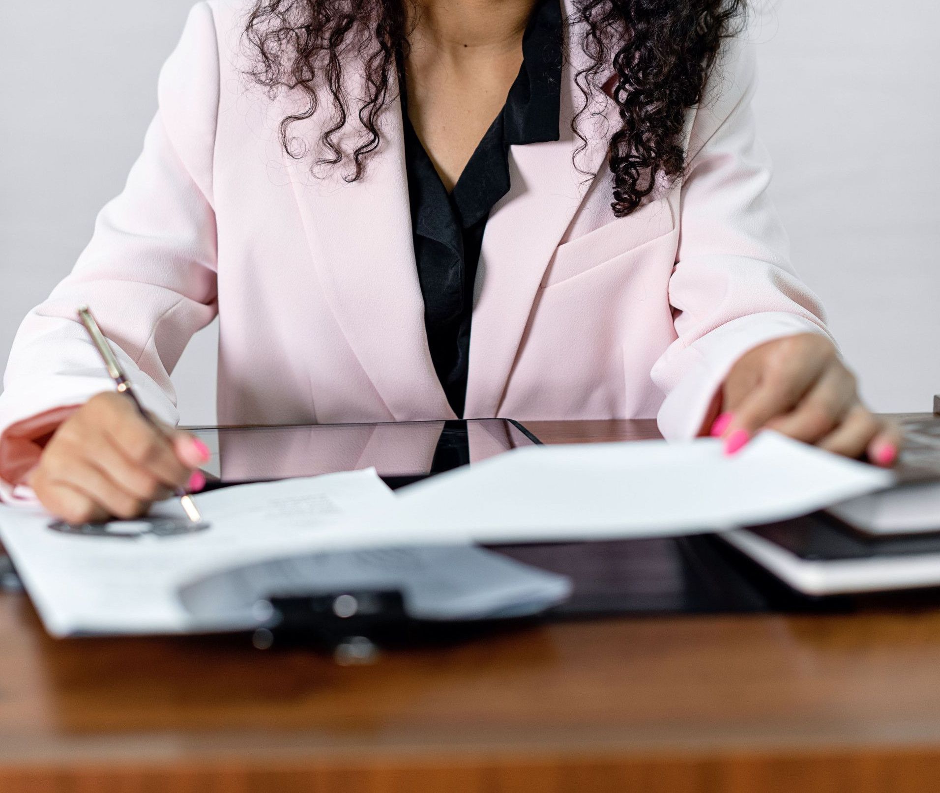 Focused businesswoman signing important documents at her office desk.